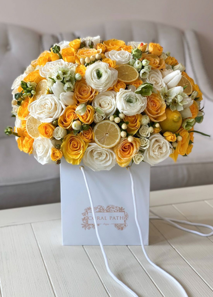 A flower arrangement featuring yellow and white flowers and real lemons.
