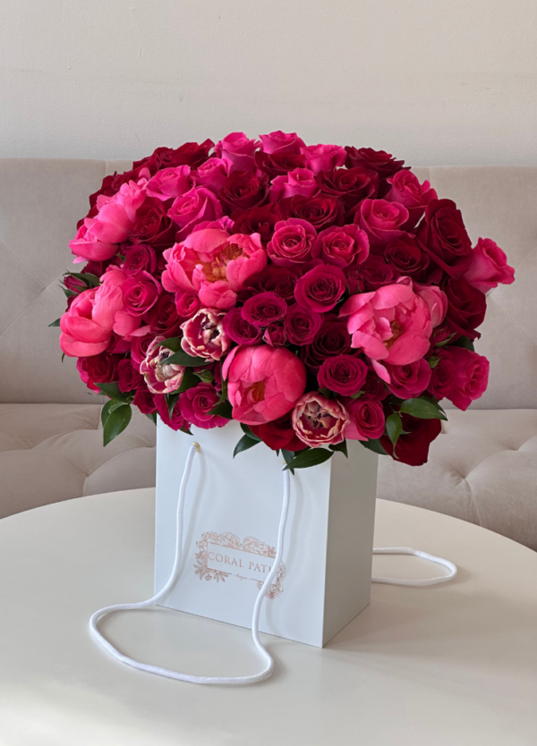 Deep red and burgundy flowers arranged in a flower bag.