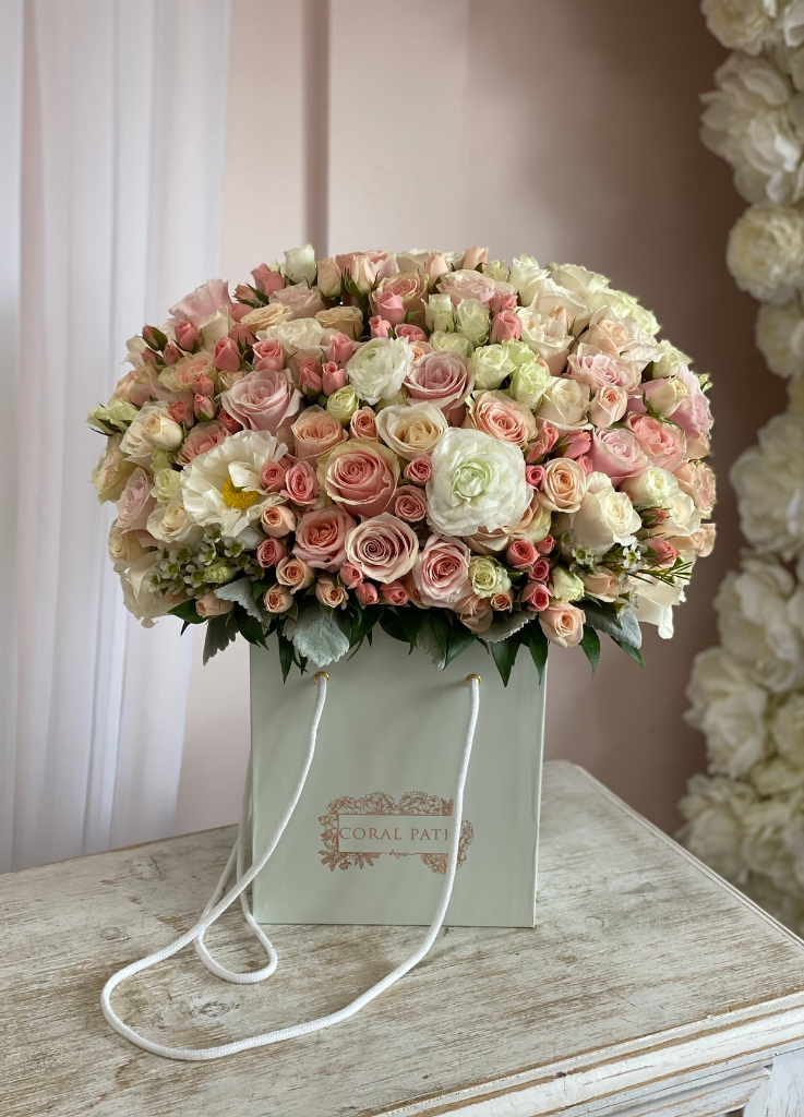 Blush and pastel flowers arranged in a flower bag.